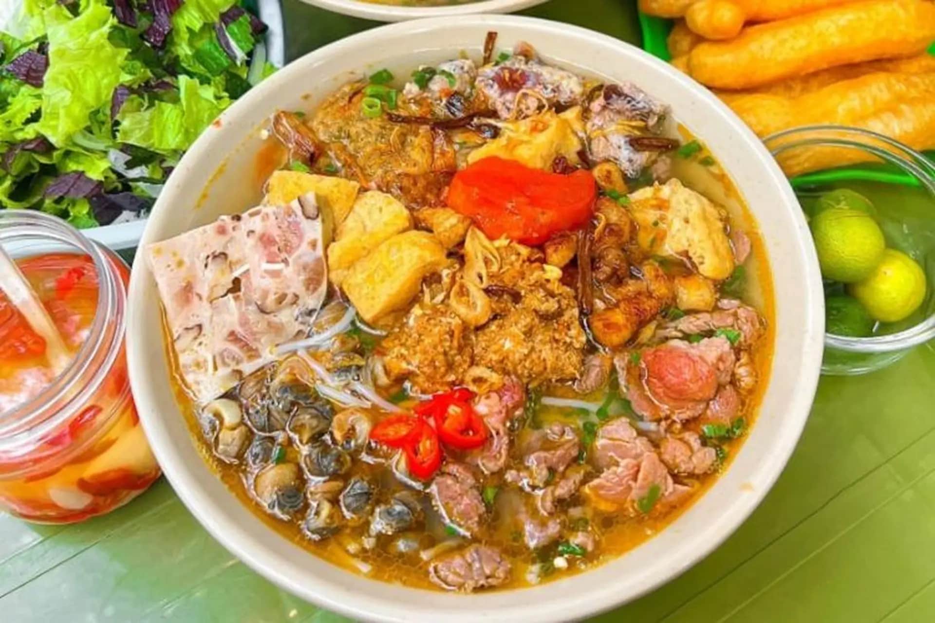 A tangy, light soup with a rich crab paste base, complemented by fresh herbs, tomatoes, and delicate vermicelli noodles